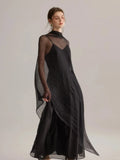 A black spaghetti strap dress layered over a light, semi-transparent tulle shawl.
